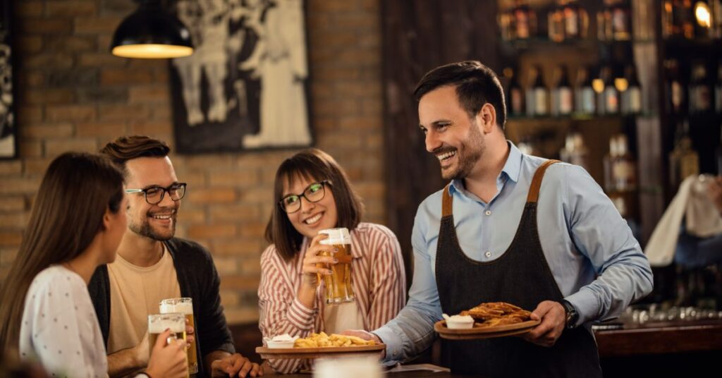 Číšník obsluhuje veselé hosty v restauraci